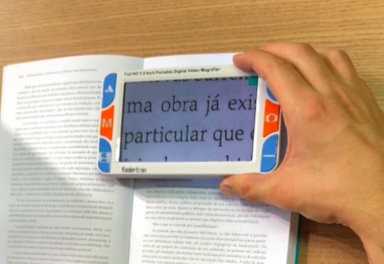 lupa eletrônica sobre um livro, mostrando uma frase do livro ampliada na tela